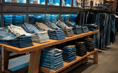 Folded Denim Jeans Displayed on Wooden Table in Clothing Store