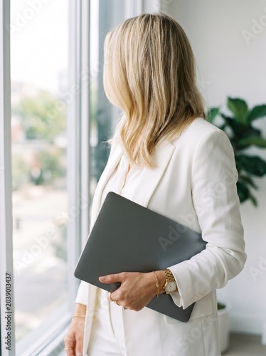 Elegant Businesswoman Working with Laptop and Coffee in Bright Modern Office