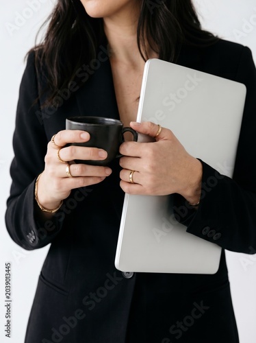 Confident Businesswoman with Laptop and Coffee in Modern Professional Workspace