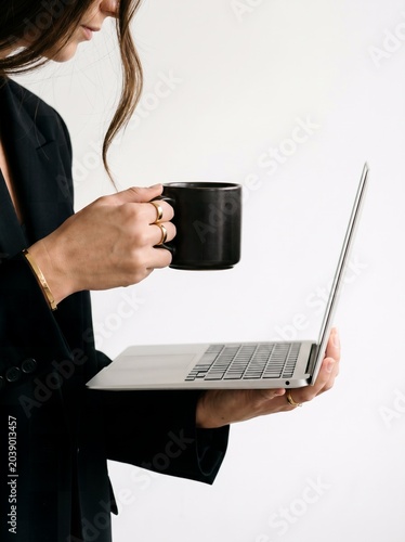 Confident Businesswoman with Laptop and Coffee in Modern Professional Workspace