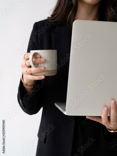 Confident Businesswoman with Laptop and Coffee in Modern Professional Workspace