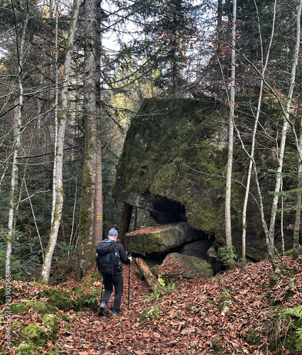 Wanderer mit Rucksack an einem großen Felsen im Märchenwald Ruhpolding im Herbst, Chiemgau, Alpen, Bayern, Deutschland