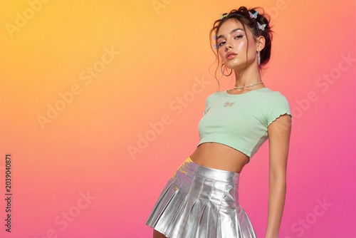 Young woman posing in y2k style with butterfly hair clips and metallic pleated skirt. Trendy fashion aesthetic with vibrant gradient background. Retro nineties inspired outfit concept