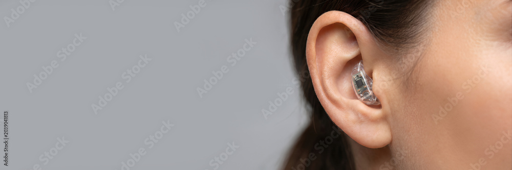 Fototapeta premium Woman ear with digital hearing aid device. Close up of medical technology for hearing loss. Senior healthcare and assistive device concept. banner format