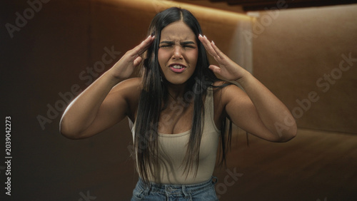 Fotografía Hispanic woman pointing finger, hands on hips, leaning forward in a recording studio booth; anger confrontation tension