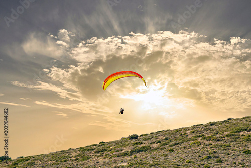 Foto Paragliding, an adventure sport, free flight in nature under an orange sky at sunset