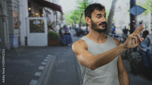 Photos Man holds up hand palm out on street wearing tanktop and beard, stopping approach and signalling refusal; rejection boundary