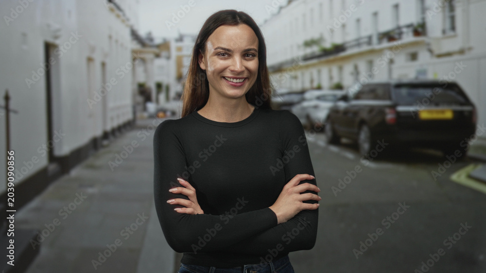 Fototapeta premium Woman with crossed arms showing bare hands on a city street lined with parked cars; confidence empowerment.