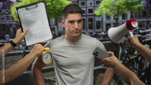 Photography Man surrounded by hands holding megaphone, clipboard, alarm clock and smartphone on an amsterdam street; stress urgency