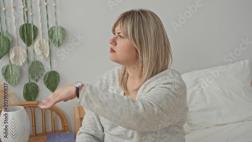 Canvastavla Woman hand mid toss gesture on bed in building, wearing gray sweater and wristwatch, frowning and displeased; annoyance dismissal