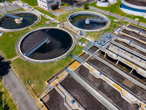 Water treatment facility processes wastewater during daylight hours while workers maintain equipment and monitor operations in an organized space