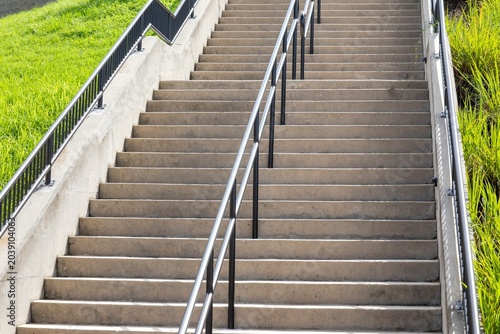Concrete staircase with metal railings, and green grass on the sides