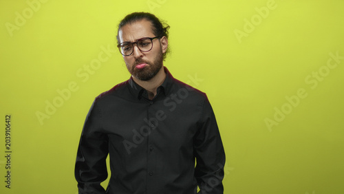 Photography Man with pouting lips and closed eyes wearing glasses and black shirt in studio against a lime green backdrop; melancholy reflection