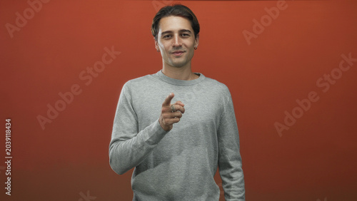 Quadro su tela Man with hands on chest gesture against red studio backdrop, later shown pointing in a six frame collage; gratitude sincerity connection