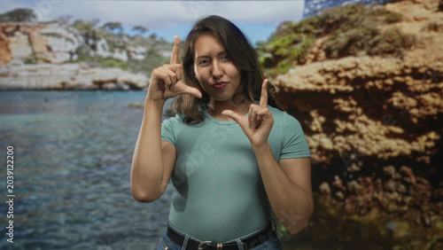 Foto Woman smiling and framing a rectangle with fingers at a seaside cove backdrop in studio, hands visible and relaxed; playful creative moment