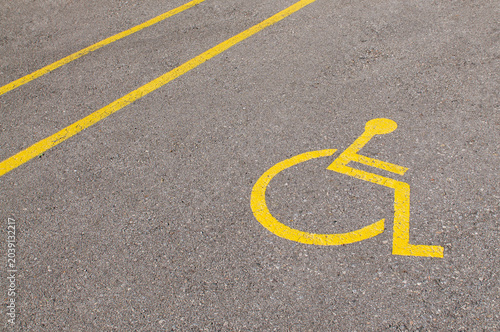 Yellow disabled parking space sign painted on stone pavement ground in Lugano Switzerland