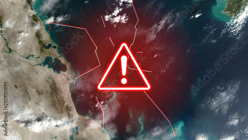 Satellite view of the Strait of Hormuz with a red warning symbol and digital lines. Concept of geopolitical tension, oil supply risks, maritime security, and global trade instability in the Gulf.