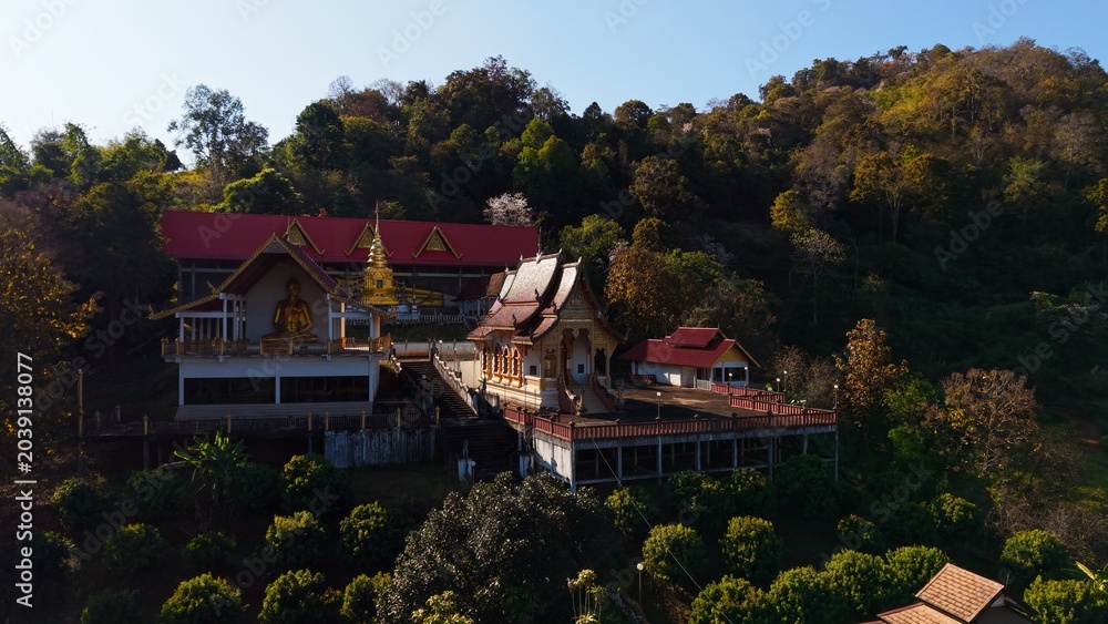 Obraz premium Wat pong yaeng nok temple complex featuring a golden buddha on a forest hillside