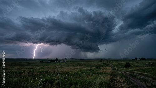 Dramatic Thunderstorm with Lightning Strike Over Open Countryside Field at Dusk