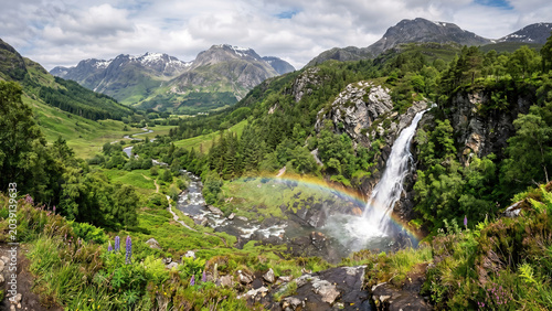 Majestic Waterfall Cascading Through Lush Green Rainforest Valley with Vibrant Rainbow