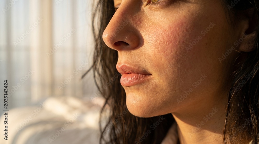 Obraz premium Close-up detail of a woman's face, lips and skin texture in soft warm morning light