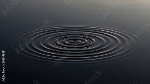 Concentric ripples spreading on the surface of dark, calm water.