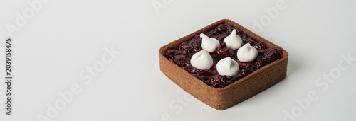 Photos A delicious tart filled with smooth cream and topped with sweet cherry jam, featuring a buttery, flaky crust, perfect for dessert or indulgent snacking