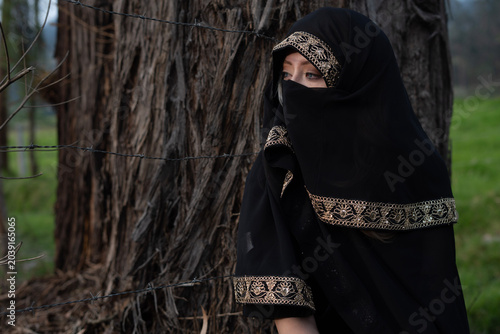 Foto Woman wearing niqab with barbed wire fence