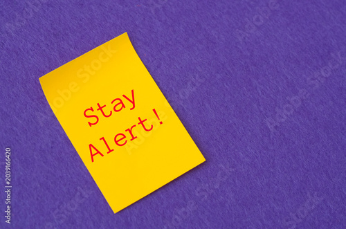 Business reminder or security concept with stay alert text on yellow note memo