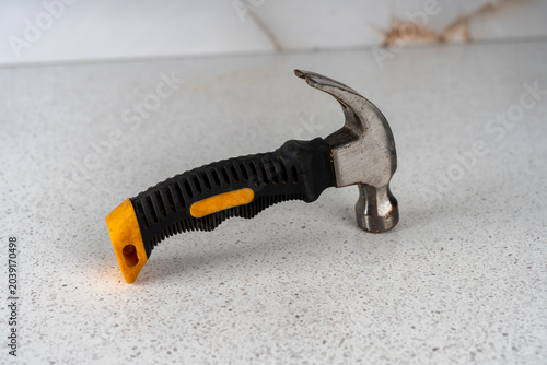 Obraz na płótnie Small stubby claw hammer tool with a short black and yellow rubberized handle, standing on a light speckled countertop