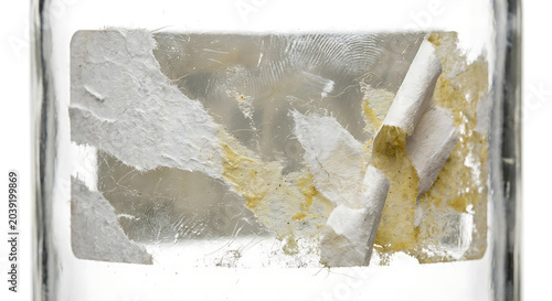Torn white sticker with adhesive residue and fingerprints on glass