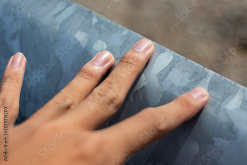 Foto human hand gently touching a galvanized steel sheet with distinct metal spangle