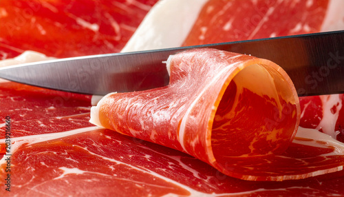 Slicing Cured Ham: A sharp knife meticulously slices a thin, delicate piece of cured ham, revealing its rich marbling and vibrant red hue. A culinary delight, perfect for gourmet dishes.