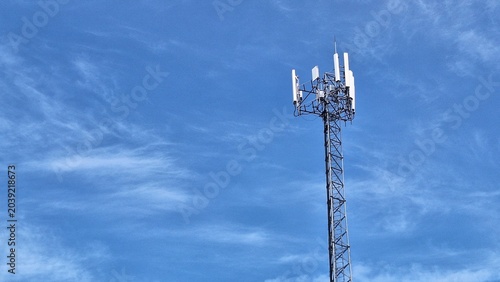 Cellular Communication Tower Against Blue Sky with Wispy Clouds and Modern Technology
