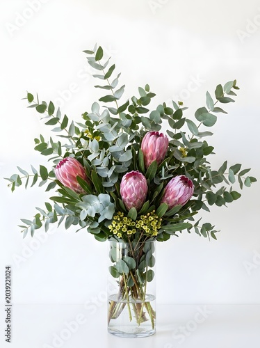 Large flower bouquet in a vase with vibrant pink protea blooms and fresh green eucalyptus foliage