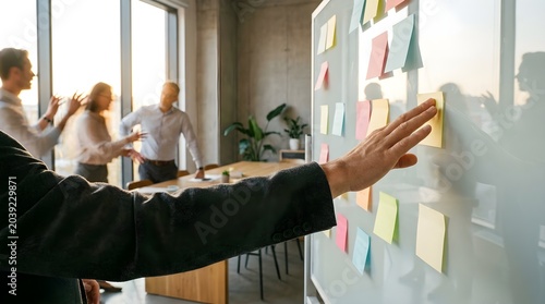 Professional business team collaborating on a strategic project, brainstorming ideas with colorful sticky notes on a whiteboard in a modern office