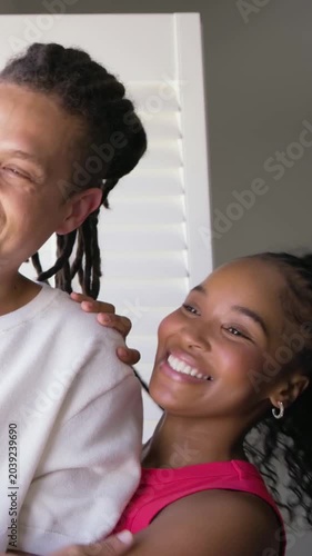 Vertical video: Sharing smiles sparking couple embracing by window in casual clothes showing love