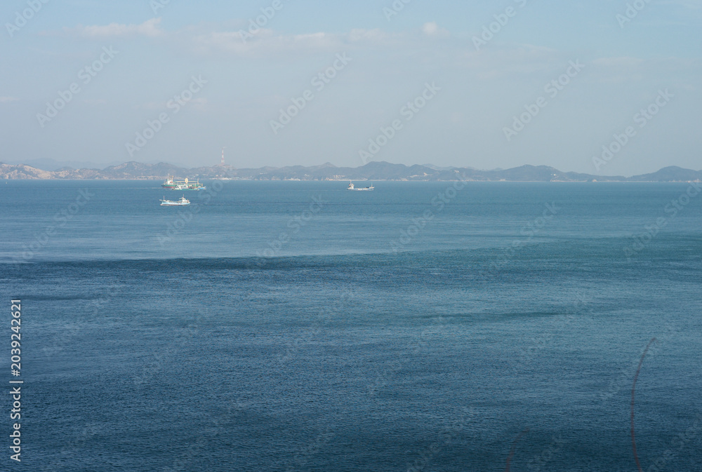 Fototapeta premium Deep big blue sea landscape with a dramatic tidal current line and cargo ships