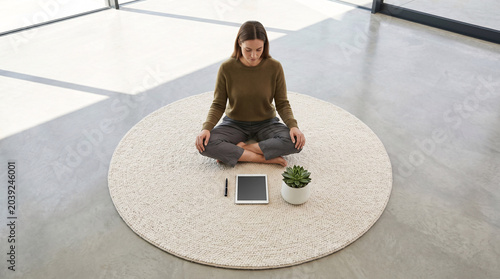 Femme méditant dans un espace minimaliste avec plante et lumière naturelle