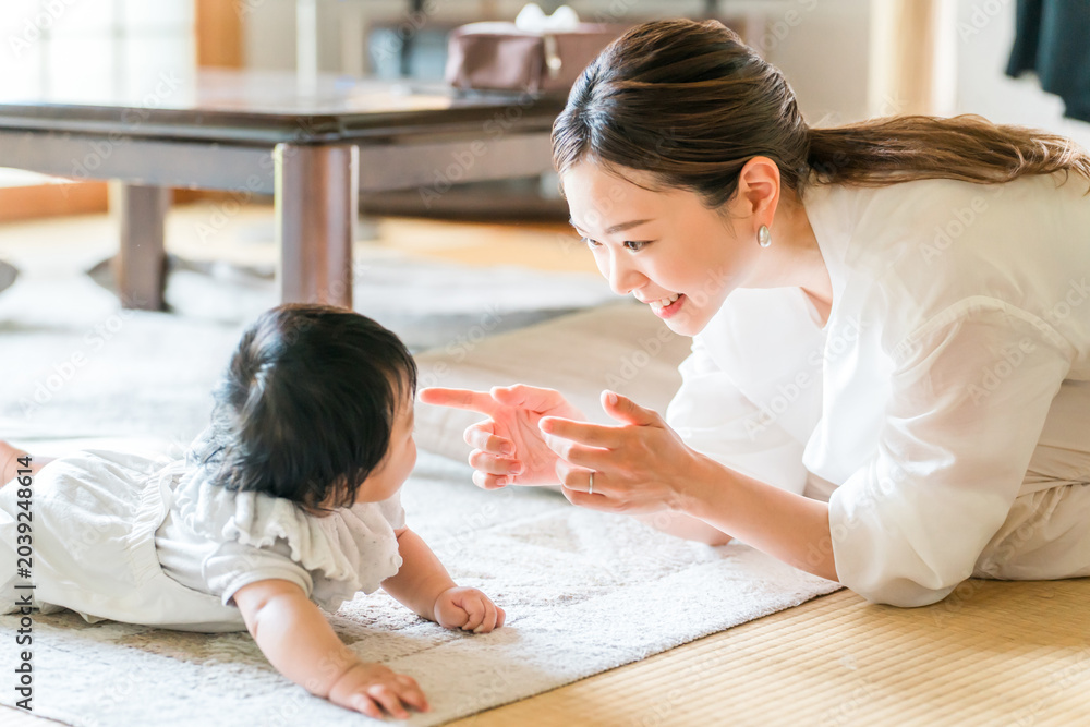 Fototapeta premium A crawling baby and a smiling mother, a mother playing with her child