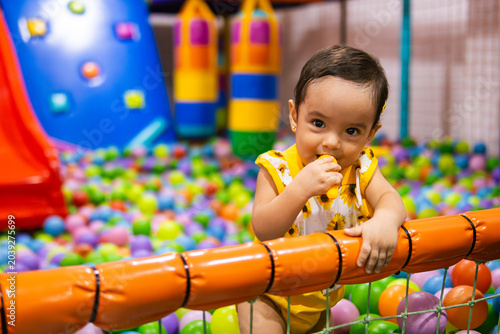 Fotografie Happy one year old latina toddler girl playing in an indoor playground, representing healthy lifestyle, wellness and early childhood development