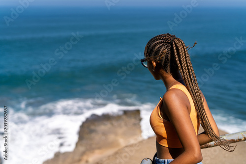 Foto Young woman enjoying expansive ocean view from cliff