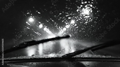 Driving Through Heavy Rain at Night: Windshield Wipers Clearing Water with City Lights in the Distance