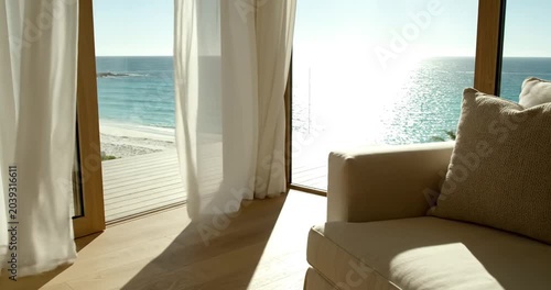 Serene coastal living room with ocean view, sunlight streaming through sheer curtains
