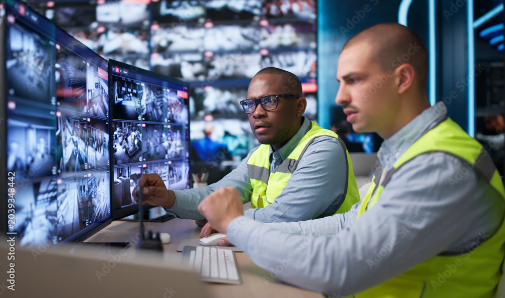 Fototapeta premium Two Security Guards Watch Surveillance Cameras Closely