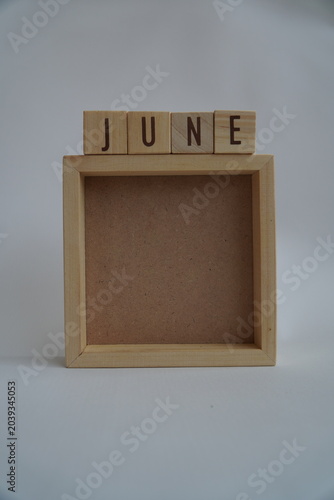 Rustic Wooden Blocks Spell Out June Above Empty Square Frame Display
