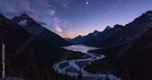 Serene twilight view of a winding river surrounded by majestic mountains and lush forests