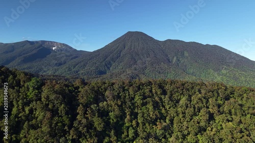 High-resolution drone video with forward motion highlights the vast green mountain and forest landscape under a clear blue sky. Mount Gede Pangrango National Park, West Java.