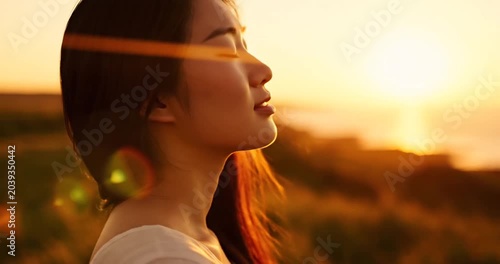 Serene woman enjoying sunset by the ocean, surrounded by nature's beauty and tranquility