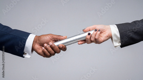 Business people passing a silver relay baton representing teamwork and corporate project handover